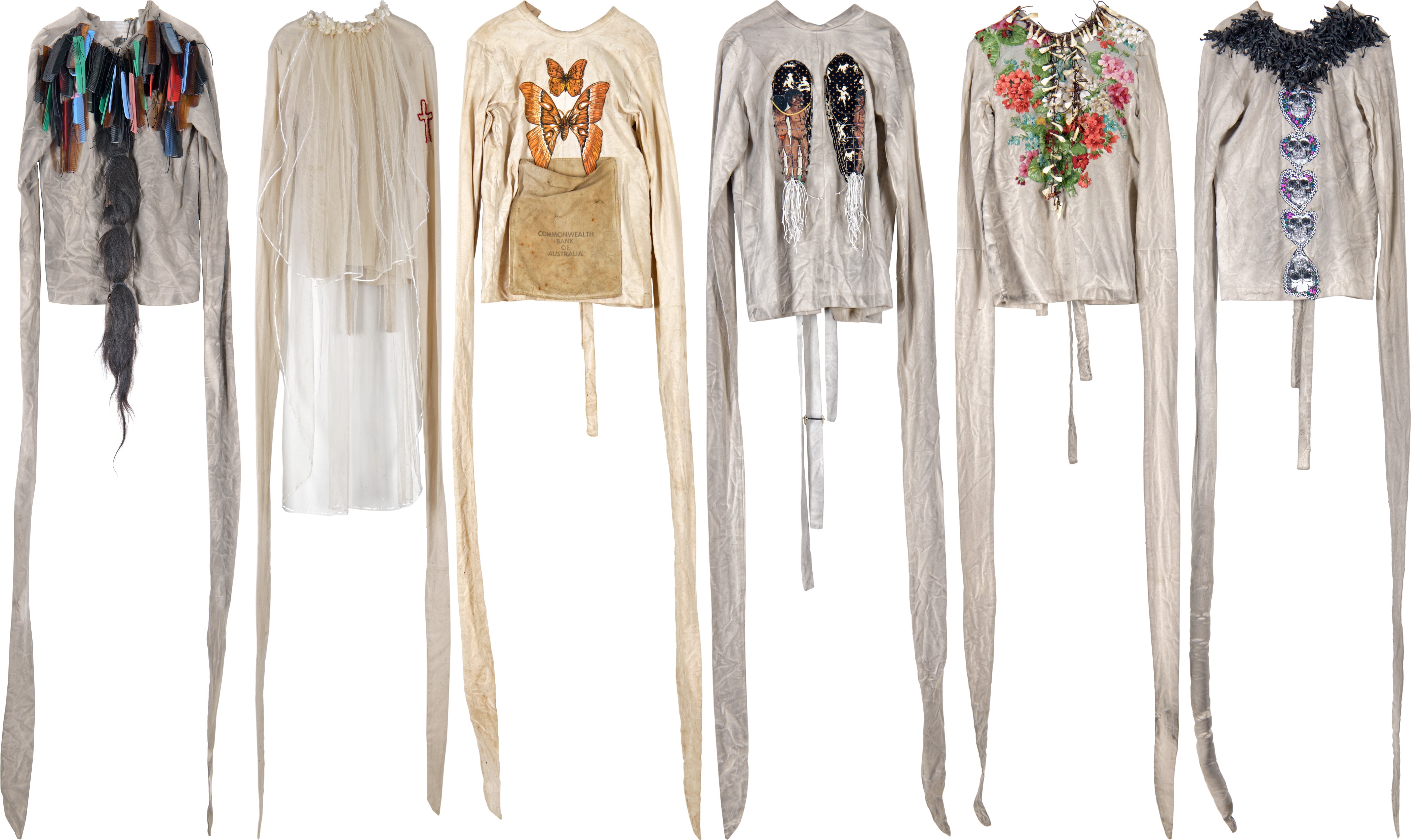 six straight jackets with images and objects attached, from left to right combs and hair, lace and embroidery, butterflies, images of people and dog muzzles, flowers and teeth, skulls and rubber